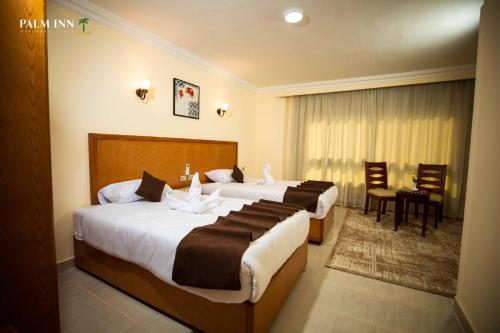 赫尔格达Palm Inn Suites Hotel的酒店客房带两张床和一张桌子以及椅子。