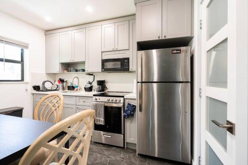 迈阿密Cozy Place的厨房配有白色橱柜和不锈钢冰箱