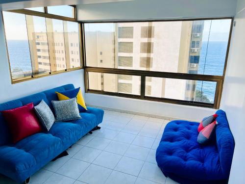 MacutoCasa de la Playa的客厅设有2张蓝色的沙发和大窗户