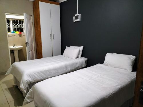 德班Inkanyezi guest house的两张睡床彼此相邻,位于一个房间里