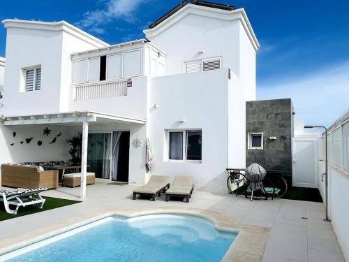 普拉亚布兰卡Lovely Villa Sanmar, heated pool的一座白色的房子,前面设有一个游泳池