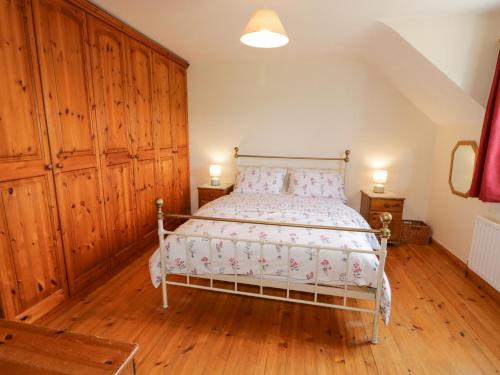 科尔雷恩Craiglea Cottage的一间卧室配有一张带木墙和木地板的床。