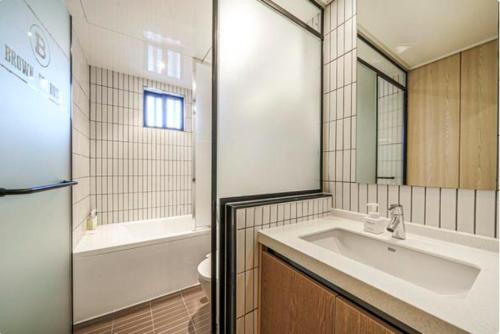 釜山Brown Dot Hotel Yeonsan的一间带水槽、浴缸和卫生间的浴室