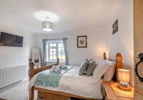 ThurgartonIvy Cottage的一间卧室配有带白色床单和枕头的床。