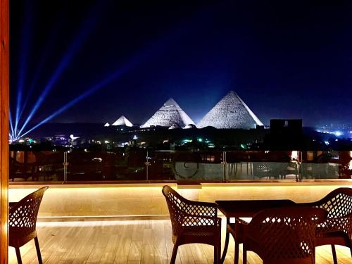 开罗Celia Pyramids View inn的一个带金字塔的阳台的桌椅