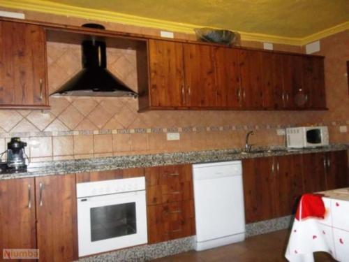 兰哈龙El Aguacate的厨房配有木制橱柜和炉灶烤箱。