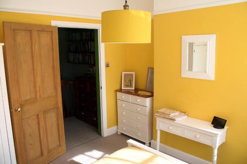 阳光港Charming 1800s Port Sunlight Worker's Cottage的黄色的房间,配有梳妆台和镜子