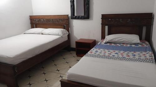 巴兰基亚HOTEL LA CORDIALIDAD的一间卧室配有两张床和镜子