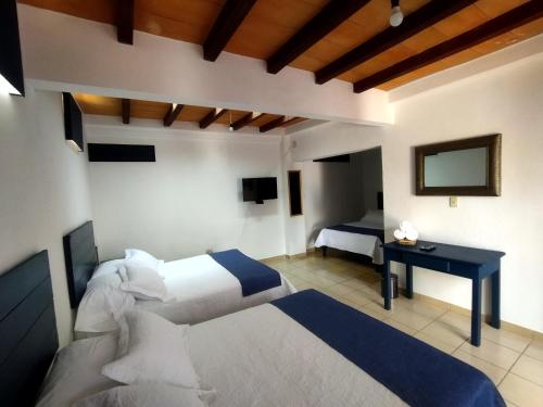 圣米格尔-德阿连德Hotel & Hostal Santuario的一间卧室配有两张床、一张桌子和一台电视。
