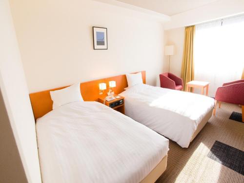 鹿儿岛鹿儿岛雷克斯登酒店的酒店客房,配有两张床和椅子