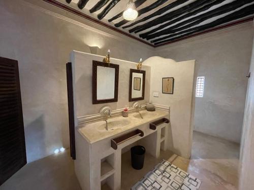 拉穆Umma House的一间带水槽和两面镜子的浴室