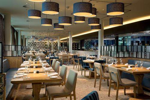 史基浦阿姆斯特丹史基浦机场希尔顿酒店的餐厅设有木桌和椅子及灯