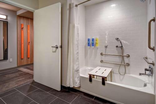 莫里斯维尔Tru By Hilton Raleigh Durham Airport的浴室配有浴缸、淋浴和长凳
