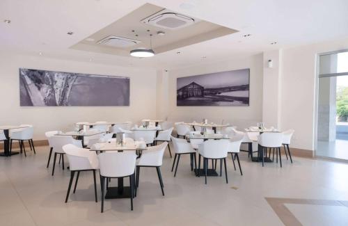 Super 8 by Wyndham Manzanillo的用餐室配有白色的桌子和白色的椅子