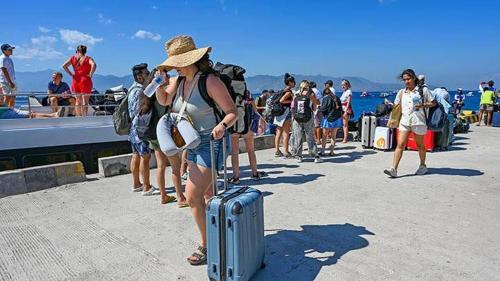 八丹拜Gilibooking ticket的一群人站在码头上,带着行李