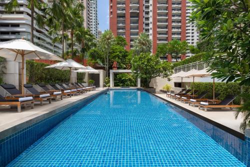 曼谷曼谷万怡酒店的一个带椅子和遮阳伞的游泳池