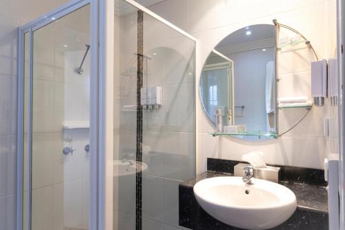 帕克斯Parkes International的浴室配有盥洗盆和带镜子的淋浴