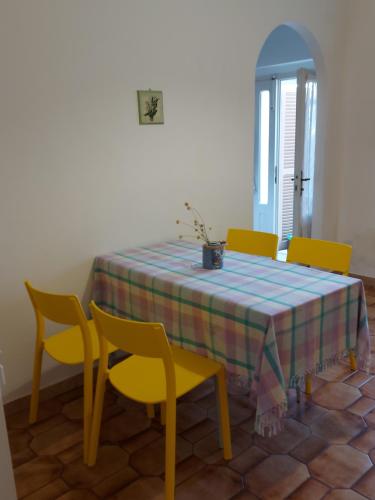洛雷托Casa nel centro storico a Loreto, 2 km dal mare的一张带黄色椅子和蓝色及黄色桌布的餐桌
