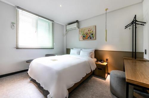 庆州Hotel No. 25 Gyeongju bus terminal的卧室配有一张白色大床和一张书桌