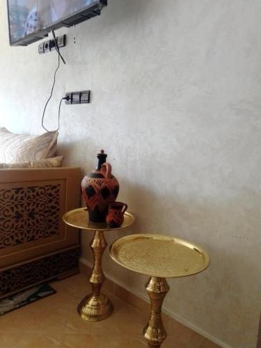 梅克内斯Meknès kamilia的一张桌子,上面有花瓶,放在床边