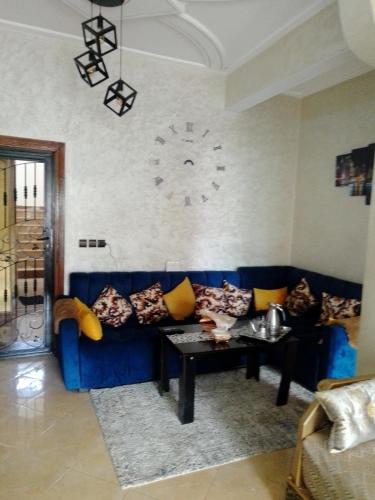 梅克内斯Meknès kamilia的客厅里的蓝色沙发,墙上挂着一个钟