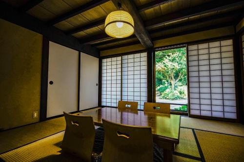镰仓市甘糟屋敷 Amakasu Yashiki KAMAKURA的一间带桌椅和窗户的用餐室