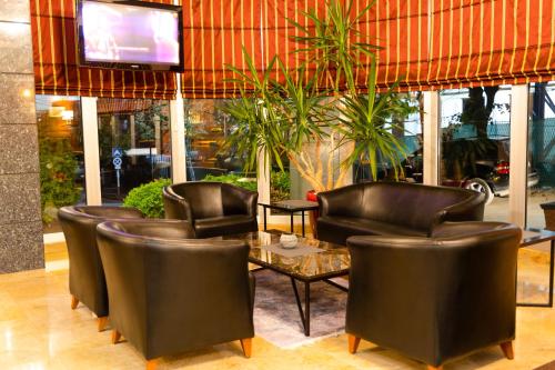 普里什蒂纳Hotel Ambasador Prishtina的餐厅设有皮椅、桌子和电视