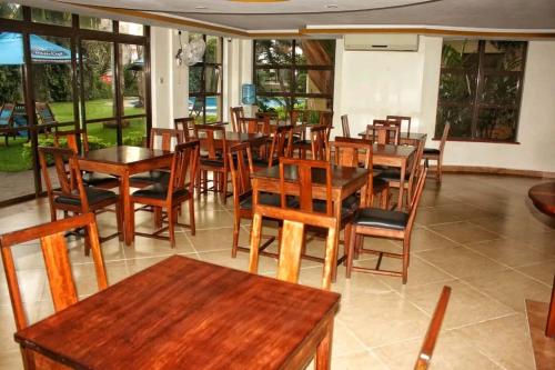尼亚利Lux Suites Impala Apartments Nyali的餐厅设有木桌、椅子和窗户。