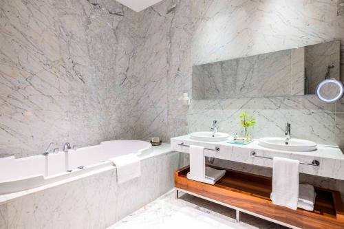 伊斯坦布尔汤姆套房酒店的白色的浴室设有2个盥洗盆和1个浴缸。