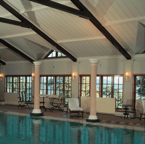 西姆拉欧贝罗伊塞西尔酒店的室内游泳池设有桌椅和窗户。