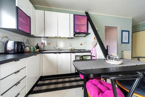 泰尔莫利A casa di Elga的厨房配有白色橱柜和一张带粉红色椅子的桌子