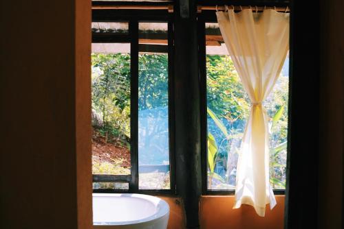 木州县Moc Chau Retreat的浴室窗户配有浴缸和窗帘