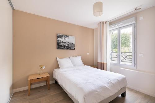 Le RaincyZenao Appart'hôtels Le Raincy的卧室配有白色的床和窗户。