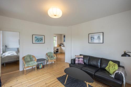孔恩斯灵比Central Lyngby Apartments的客厅配有黑色真皮沙发和椅子
