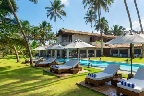 本托塔Villa Thamburu, Bentota的一个带游泳池、椅子和棕榈树的度假村