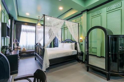 曼谷DE Phanakron Boutique Hotel的一间卧室设有天蓬床和绿色的墙壁