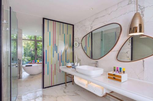 三亚三亚金都蔚景温德姆酒店（大东海）的浴室配有盥洗盆、镜子和浴缸
