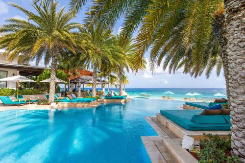 Shoal Bay VillageZemi Beach House, LXR Hotels & Resorts的一座棕榈树和海洋游泳池