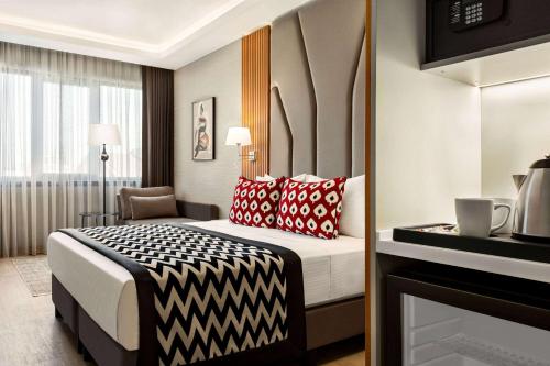 伊斯坦布尔Ramada Encore by Wyndham Istanbul Sisli的酒店客房配有一张带红色和黑色枕头的床。