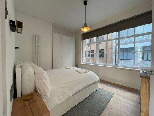利物浦Stylish city-centre apartment with balcony的卧室设有白色的床和大窗户