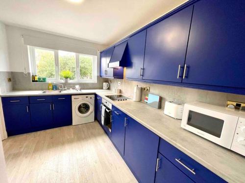 斯丹斯达蒙费雪特Large 5 bed detached house near Stansted Airport的厨房配有蓝色橱柜和白色微波炉