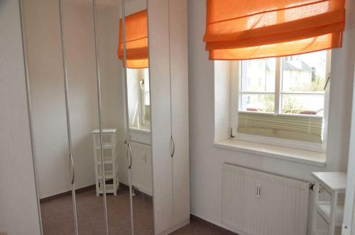 萨斯尼茨Villa Johanna mit herrlichem Seeblick的一间设有两扇窗户和橙色窗帘的房间