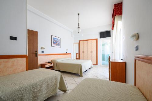 丽都迪萨维奥Hotel de Paris的酒店客房设有两张床和窗户。