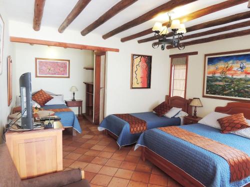 莱瓦镇Hotel Villa Cristina的一间设有三张床和电视的房间