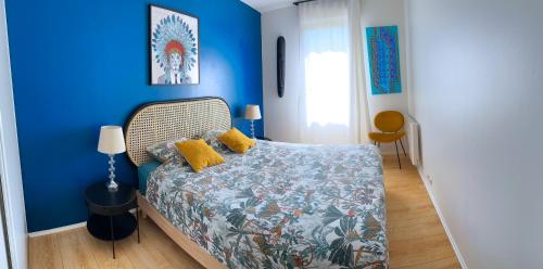 圣但尼Charme et Douceur By UTA HOUSE的一间卧室拥有蓝色的墙壁,配有一张带黄色枕头的床。