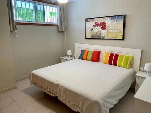 圣地亚哥港TAGARA - 2 pools, ocean view, Puerto de Santiago的一间卧室配有一张带两个色彩缤纷的枕头的床