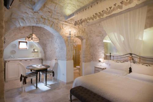 阿尔贝罗贝洛浪漫特鲁利酒店的一间卧室设有一张大床和石墙