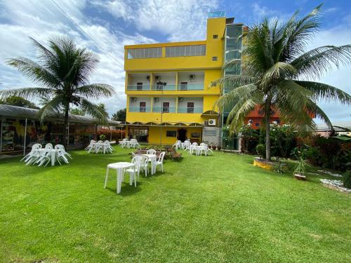 伊塔帕里卡岛维拉克鲁兹Chesmar Plaza Hotel的院子里设有白色的桌椅的酒店