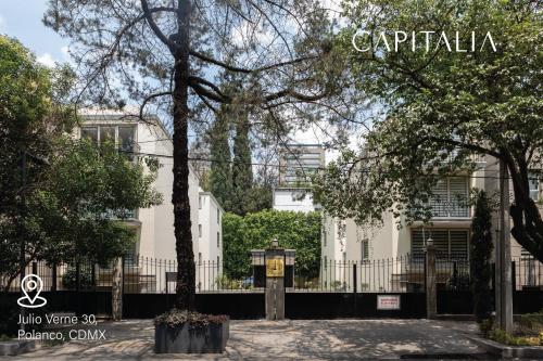 墨西哥城Capitalia - Apartments - Polanco - Julio Verne的前面有栅栏和树木的建筑