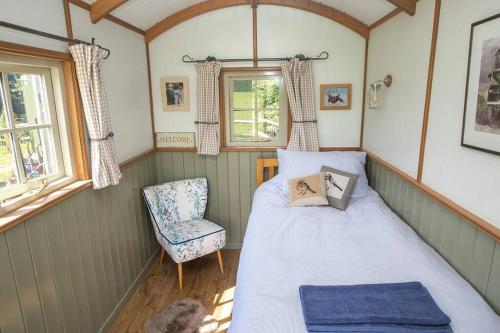 阿伦德尔Shepherds Huts Tansy & Ethel in rural Sussex的一间小卧室,配有一张床和一把椅子